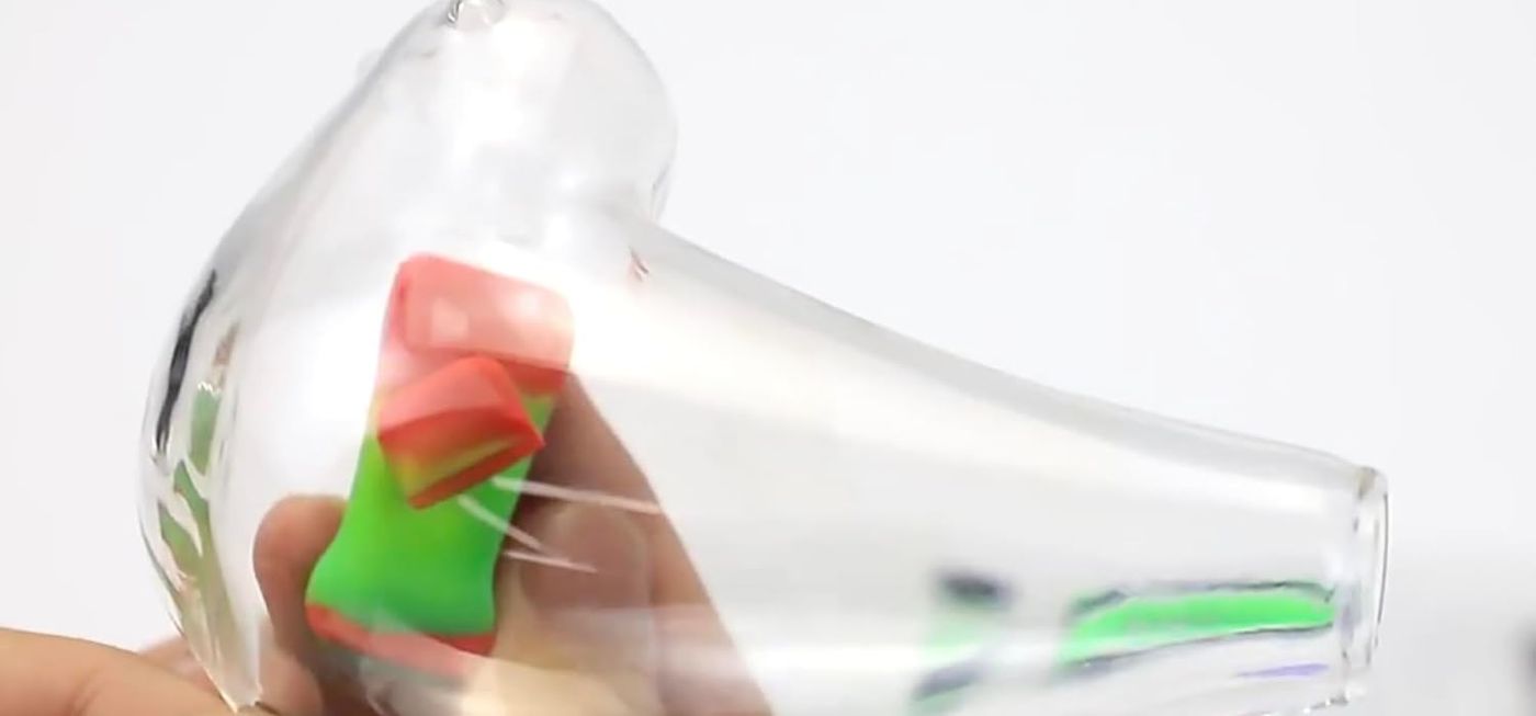 Real photo: hand cleaning a clear glass pipe with a Green Piece silicone magnetic glass cleaner